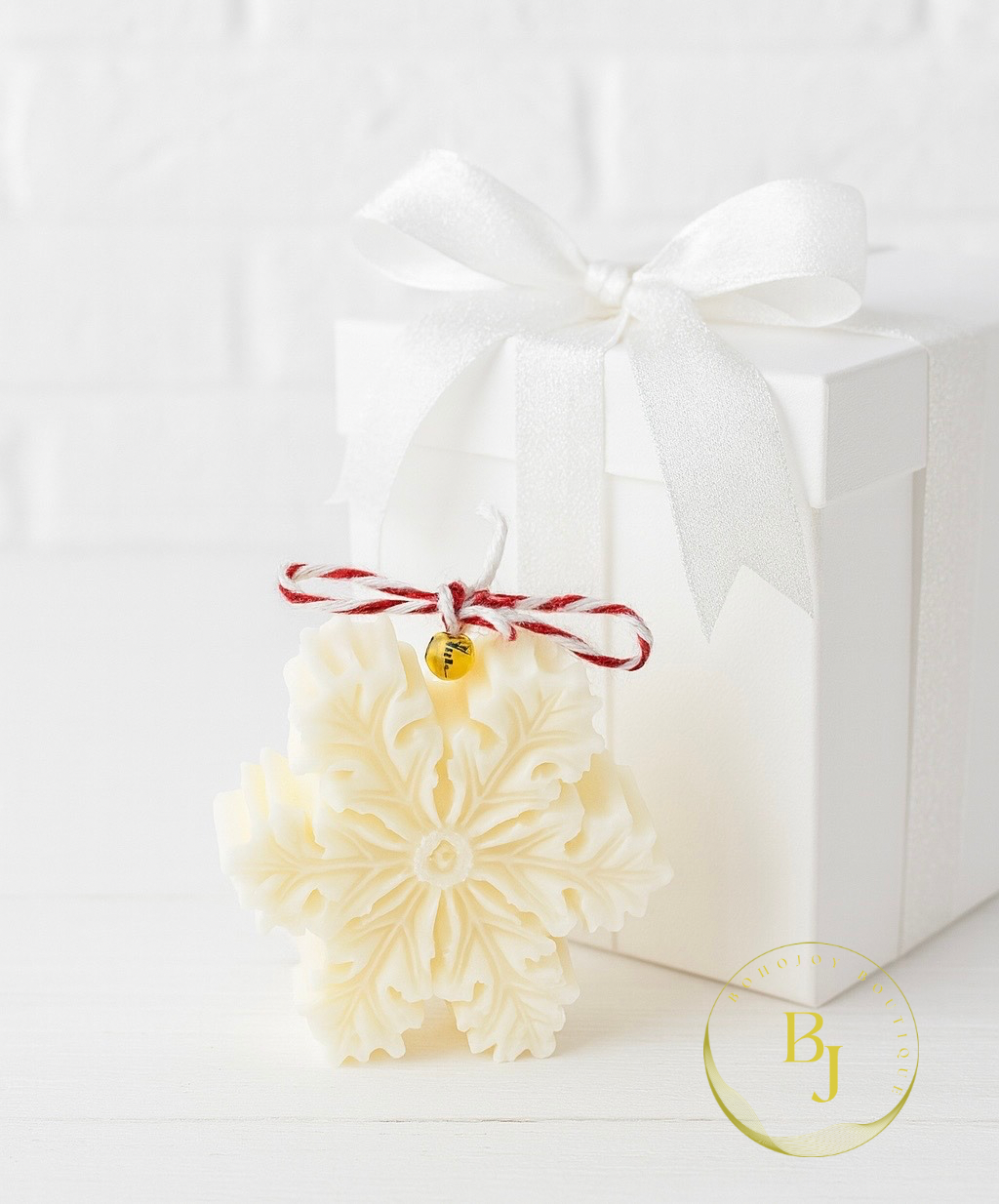 Bougie Flocon de Neige en forme de flocon, fabriquée à la main, avec un joli nœud, présentée dans une boîte blanche.